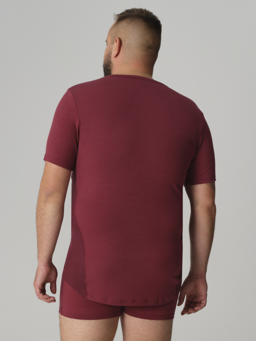 Rückansicht: Mann trägt Herren Shirt kurzarm aus Merinowolle Farbe Merlot/Porto