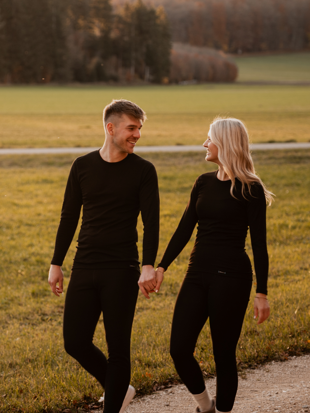Paar trägt schwarze Unisex-Funktionswäsche von Comazo bei einem Spaziergang – atmungsaktive und temperaturregulierende Basics für jedes Wetter