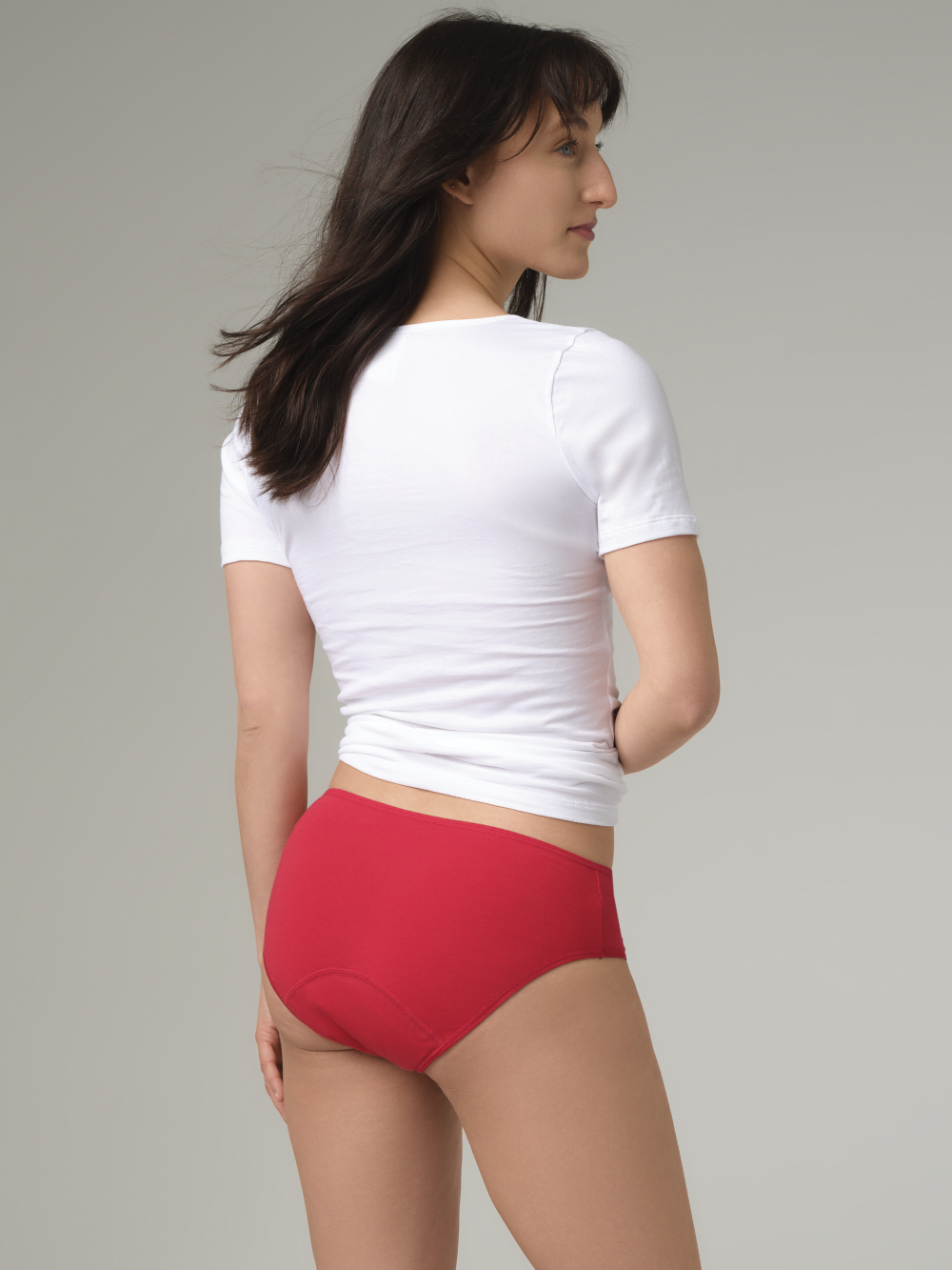 Rückansicht: Frau trägt Fairtrade Perioden-Slip "Medium" von Comazo in der Farbe Rubinrot mit integriertem Auslaufschutz