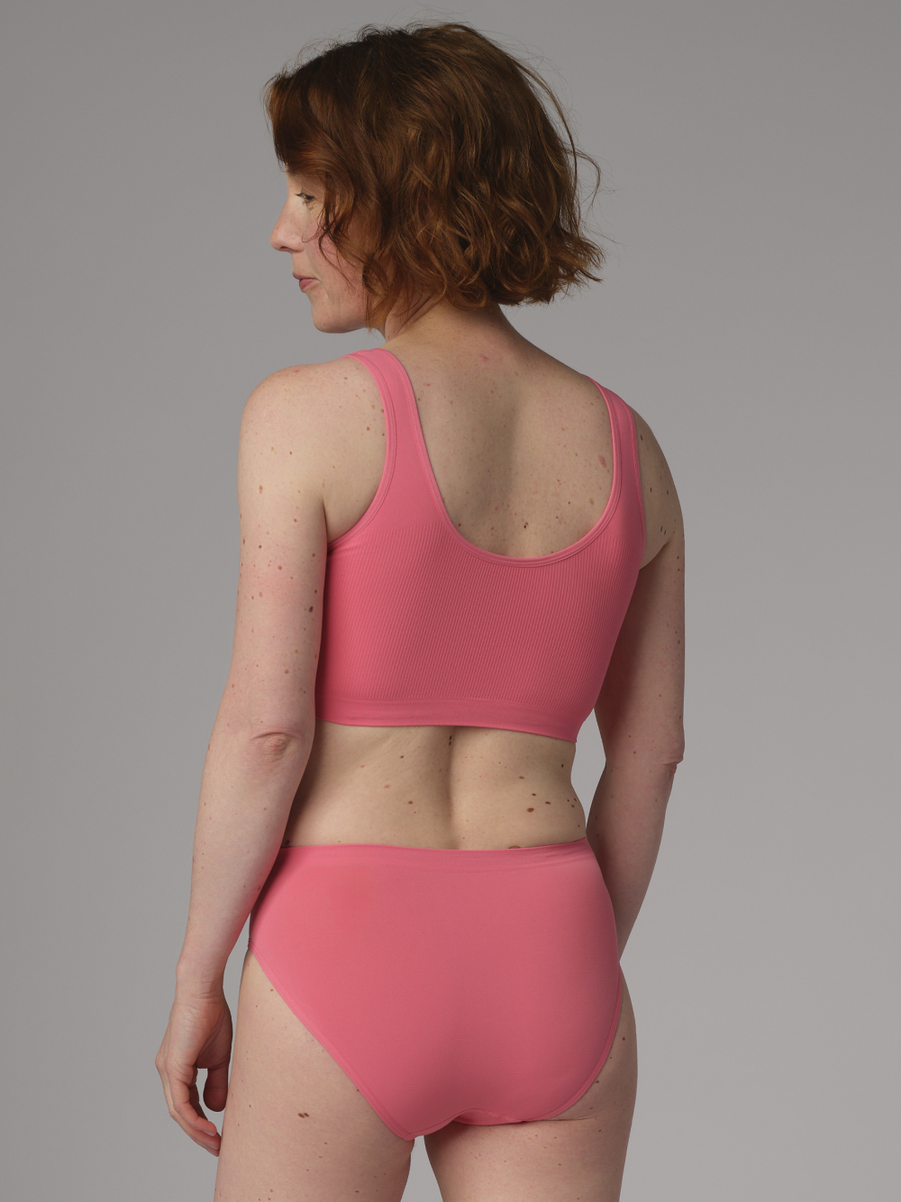 Rückansicht: Frau trägt Seamless Soft-BH/Sport BH von Comazo in der Farbe Grenadine