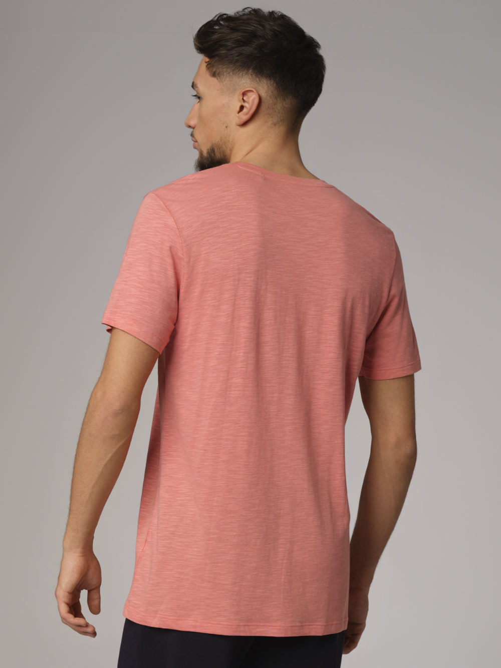 Back view: Man wearing Comazo men's short-sleeve shirt made from slub yarn in papaya color.
