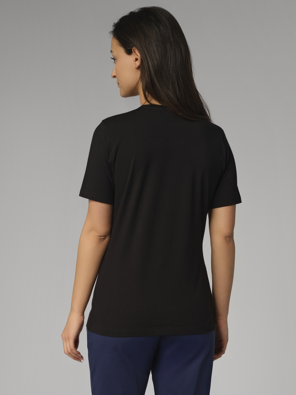 Rückansicht: Frau trägt Basic Shirt kurzarm von Comazo in der Farbe Schwarz mit Rundhalsausschnitt.