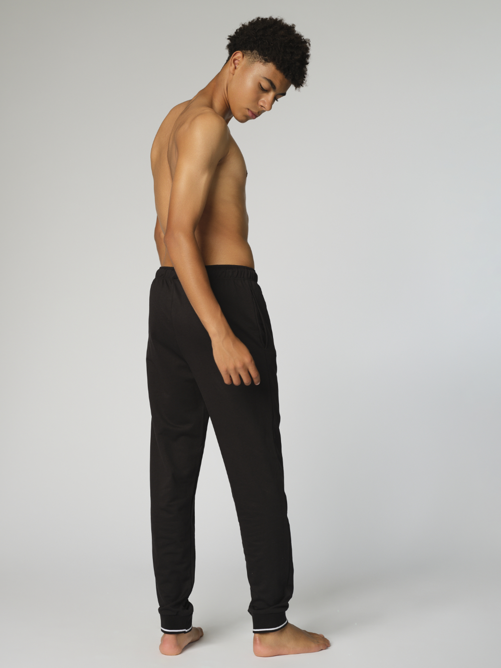 Rückansicht: Mann trägt Hose lang mit Bündchen von Comazo in der Farbe Schwarz mit Kordelzug und seitlichen Eingriffstaschen