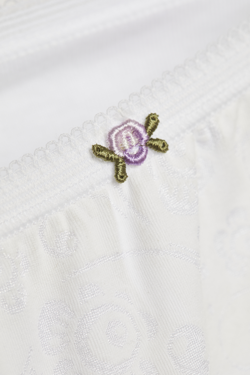 Detailbild Hüft-Slip von Comazo in der Farbe Weiß aus 100% Baumwolle mit zartem Stickblümchen.