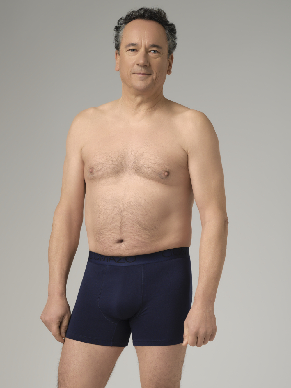Front view: Man wearing Comazo trunks in navy with logo waistband
