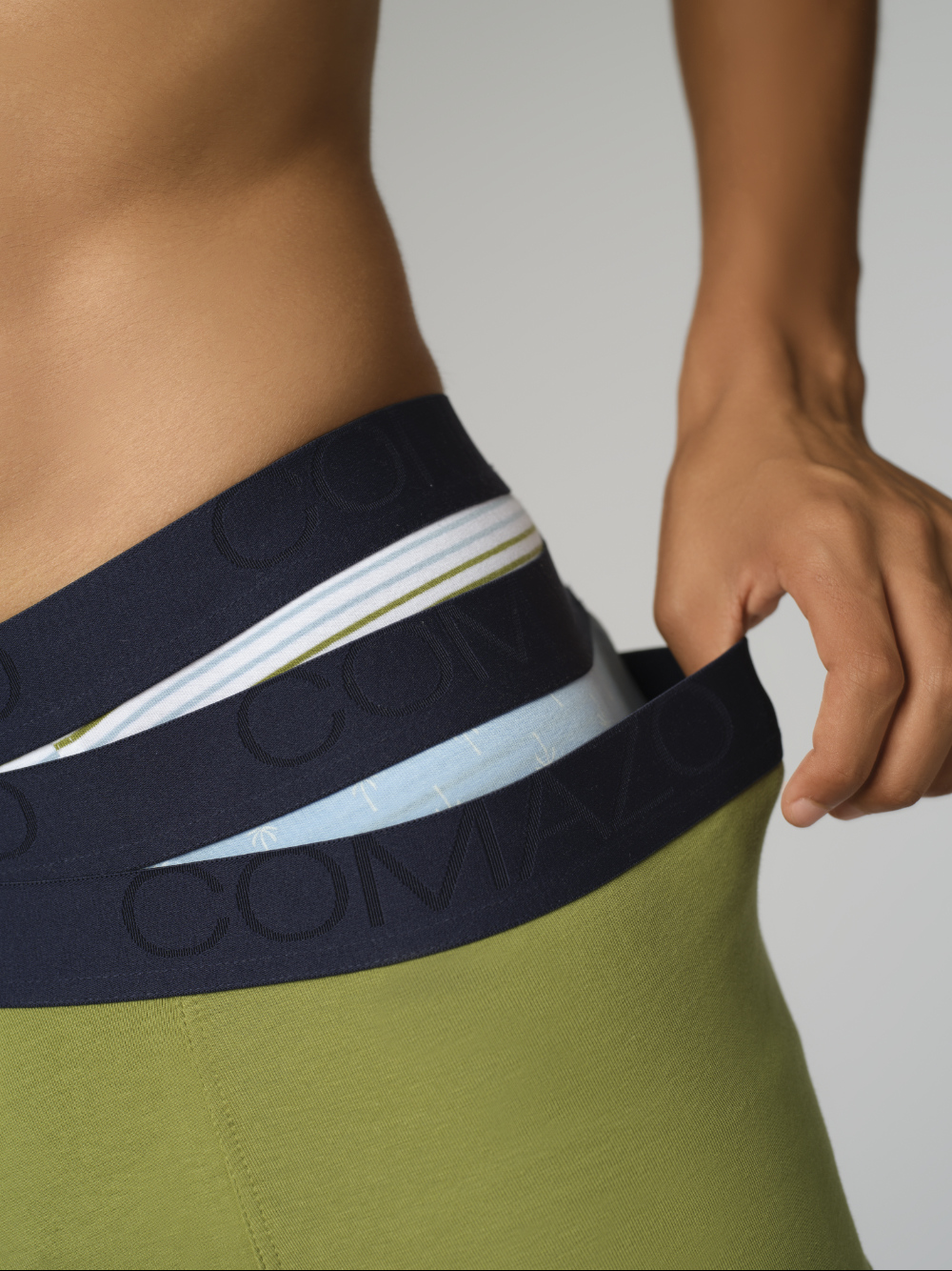 Nahaufnahme Vorderansicht: Mann trägt  alle drei Pants aus 3er Pack "Oliv/Blau" von Comazo in verschiedenen Mustern und Farben