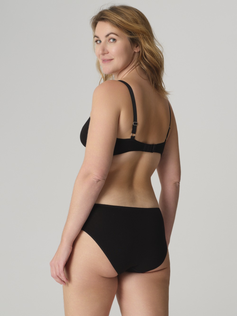 Rückansicht: Frau trägt Fairtrade BH ohne Bügel von Comazo in der Farbe Schwarz mit Spacer