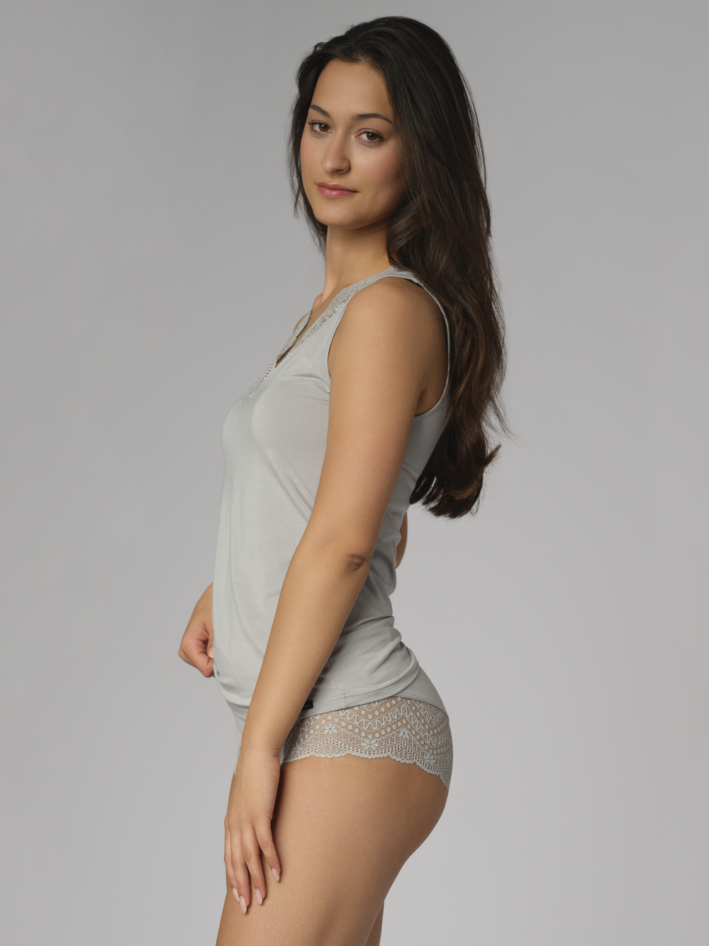 Seitenansicht: Frau trägt Comazo Damen Unterhemd Farbe Grau aus Modal mit Spitze