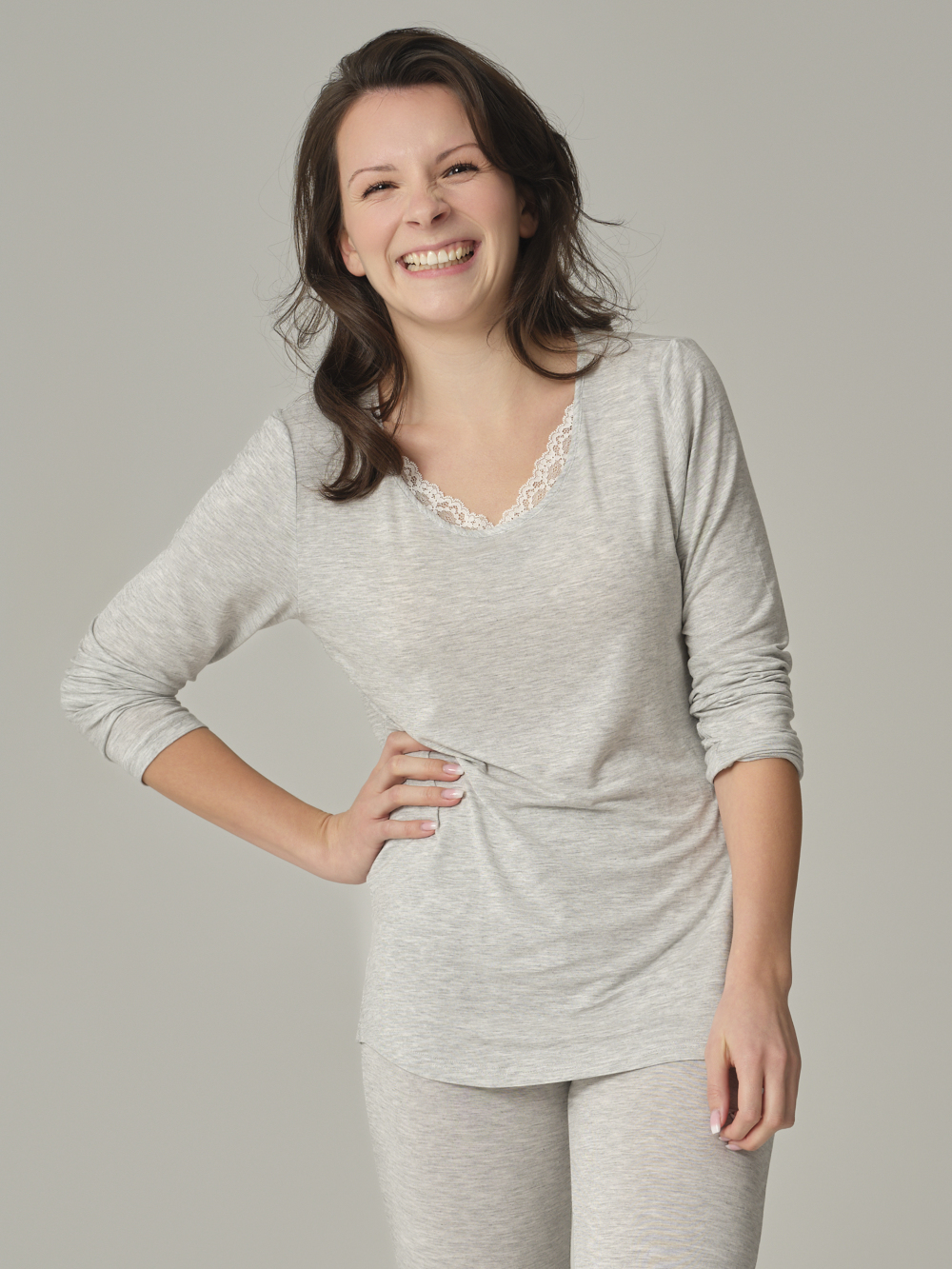 Vorderansicht: Frau trägt Langarm-Schlafshirt aus Micromodal von Comazo in der Farbe Grau mit zarten Spitzen-Details