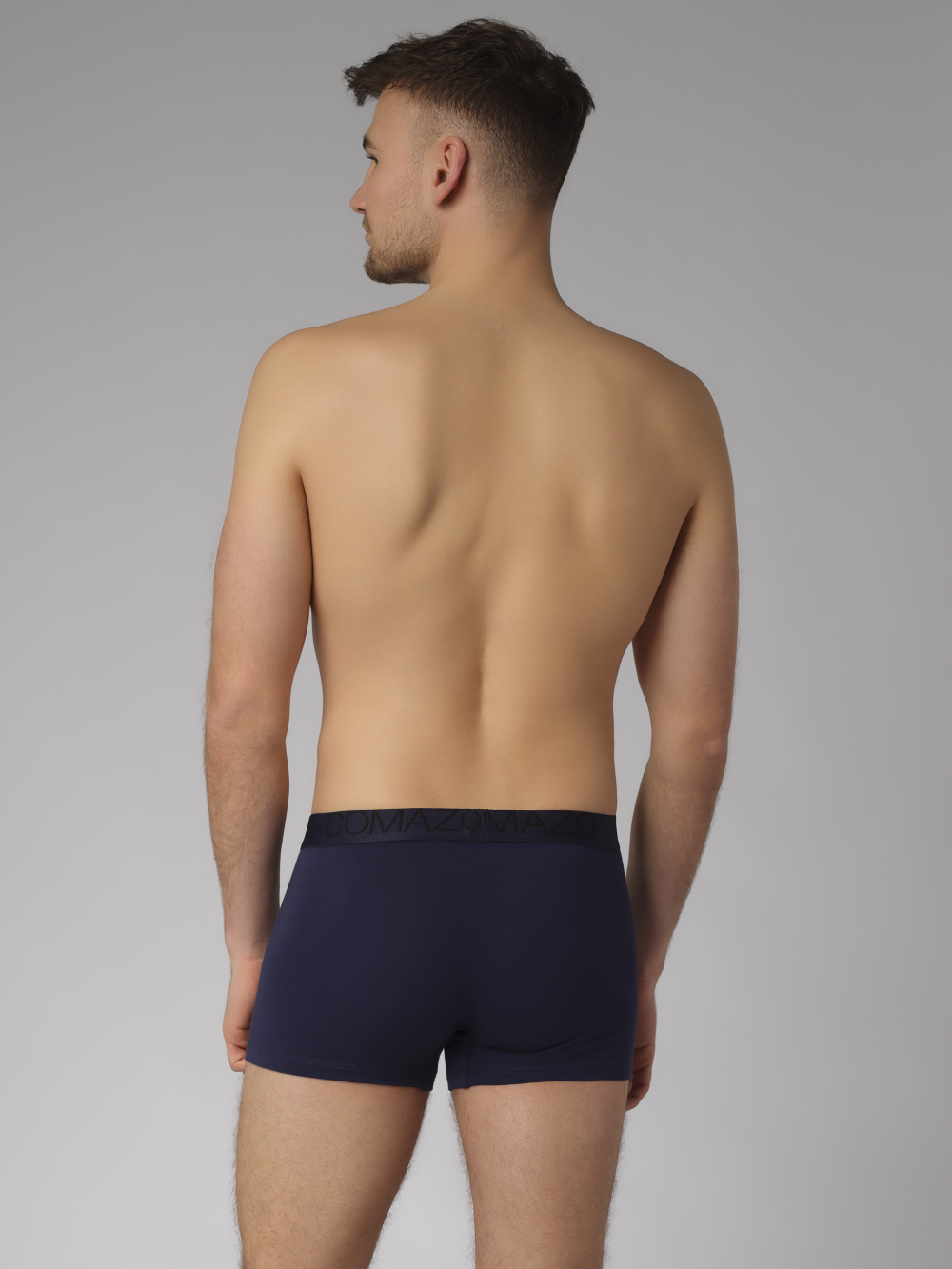 Rückansicht: Mann trägt Fairtrade Pants von Comazo in der Farbe Marine mit Webgummi mit Schriftzug