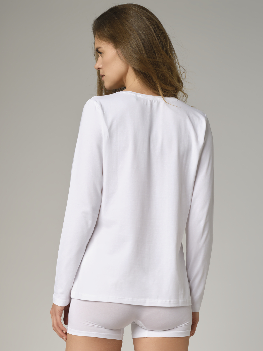 Rückansicht: Frau trägt Basic Shirt langarm von Comazo in der Farbe Weiß mit Rundhalsausschnitt