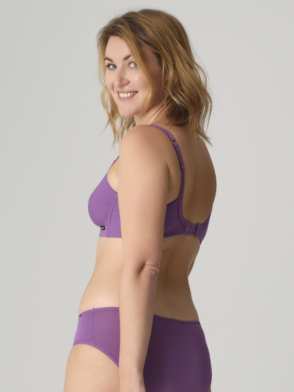 Rückansicht: Frau trägt Comazo BH ohne Bügel Farbe Purple