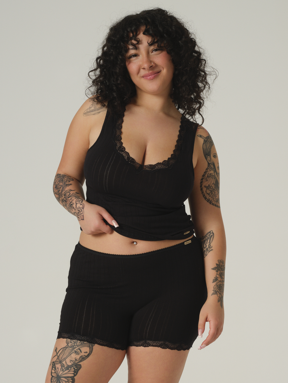 Vorderansicht 2: Frau trägt Fairtrade Panty von Comazo in der Farbe Schwarz mit Spitzendetails aus Single Jersey mit Nadelzug