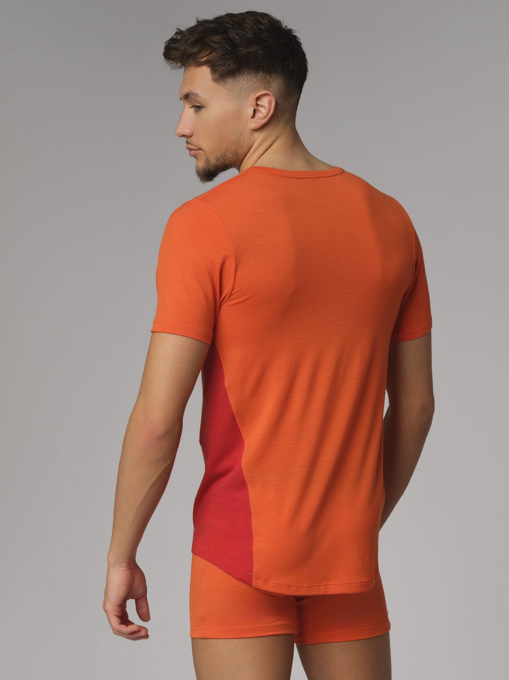 Rückansicht: Mann trägt Comazo Herren Shirt kurzarm aus Merinowolle Farbe Orange/Granat