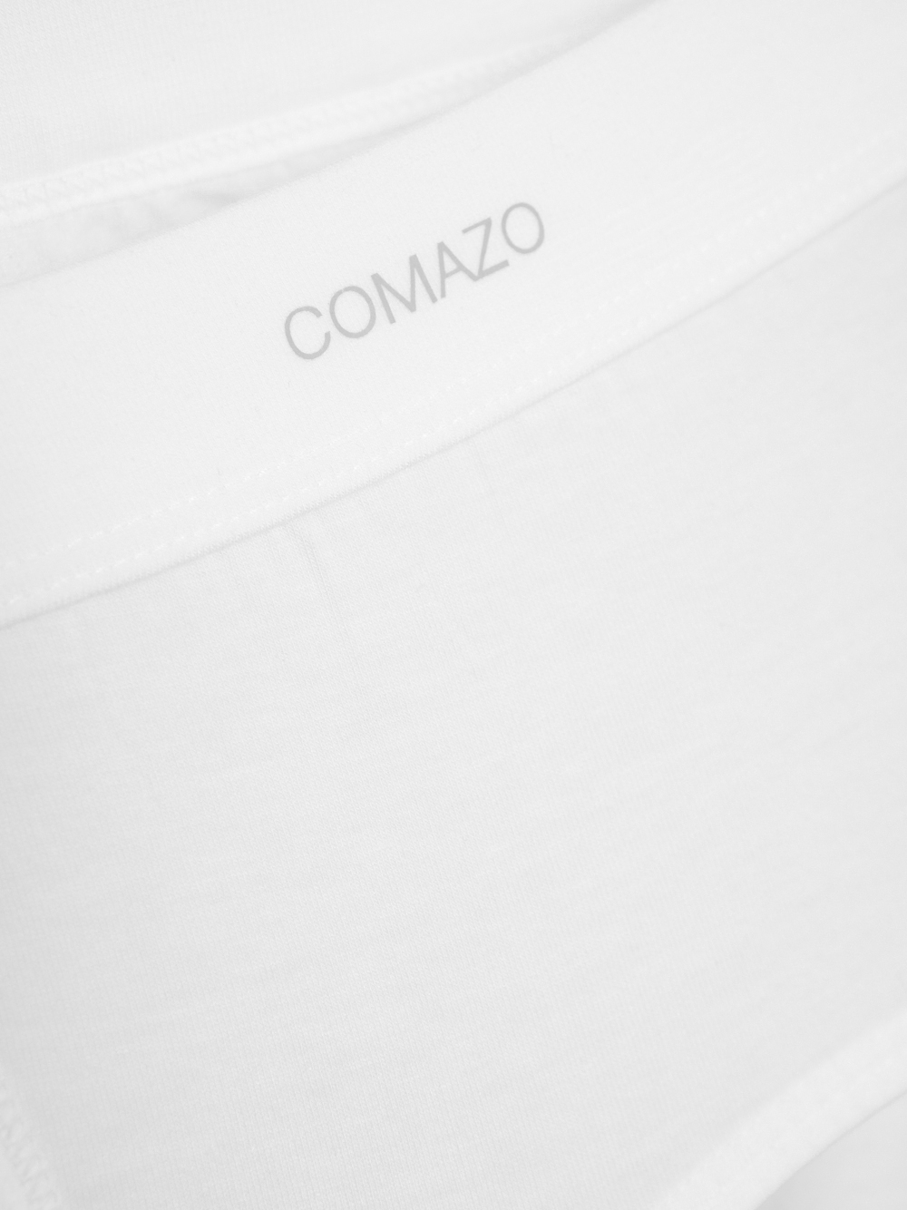 Vorderansicht: Mann trägt Slip mit Eingriff aus Baumwolle und Micromodal von Comazo in der Farbe Weiß mit geprägtem Stoffgummibund