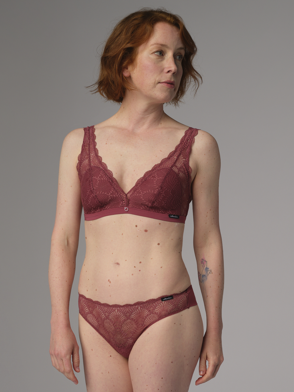 Vorderansicht: Frau trägt Soft-BH von Comazo in der Farbe Berry mit zarter Spitze und rundem Accessoire-Anhänger.