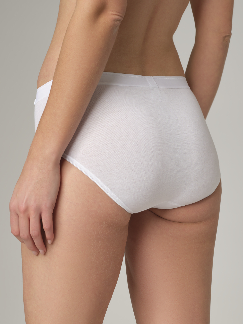 Rückansicht: Frau trägt Midi-Slip von Comazo in der Farbe Weiß Feinripp-Qualität