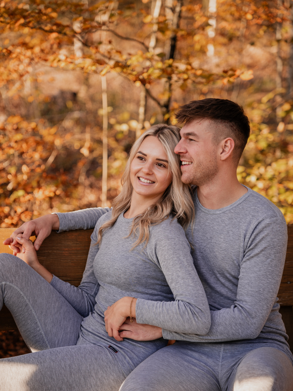 Ein Pärchen sitz auf einer Bank und beide tragen ein Unisex Funktionsshirt "warm extra" langarm von Comazo in der Farbe Grau-Melange