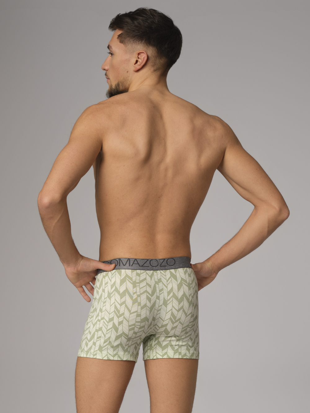 Rear view: Man wearing Comazo men's trunks in printed lime cream