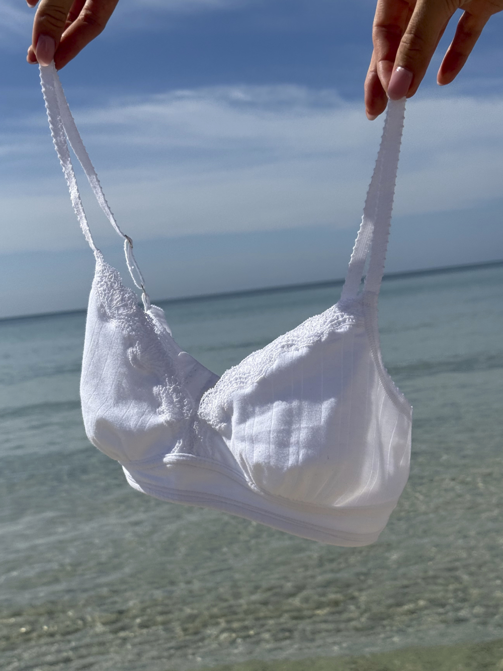 Fairtrade-BH aus Bio-Baumwolle von Comazo, gehalten vor klarem Meerwasser – nachhaltige und hautfreundliche Unterwäsche