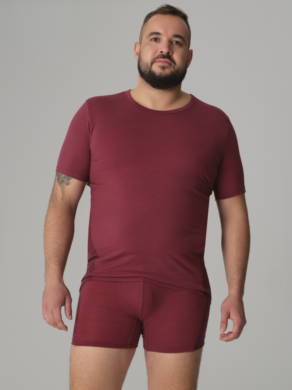 Vorderansicht: Mann trägt Herren Shirt kurzarm aus Merinowolle Farbe Merlot/Porto