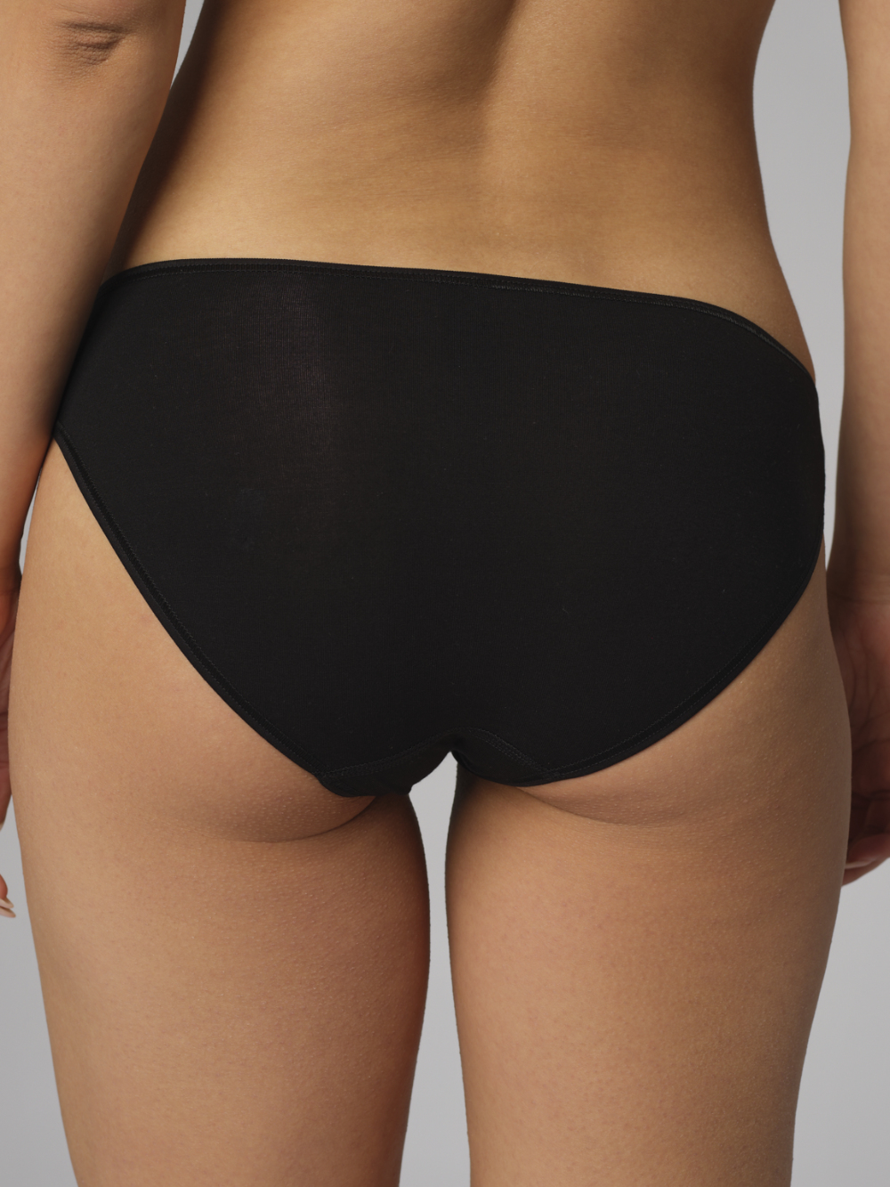 Rückansicht: Frau trägt Jazz-Pants von Comazo in der Farbe Schwarz aus MicroModal® mit edlem Schmuck-Anhänger