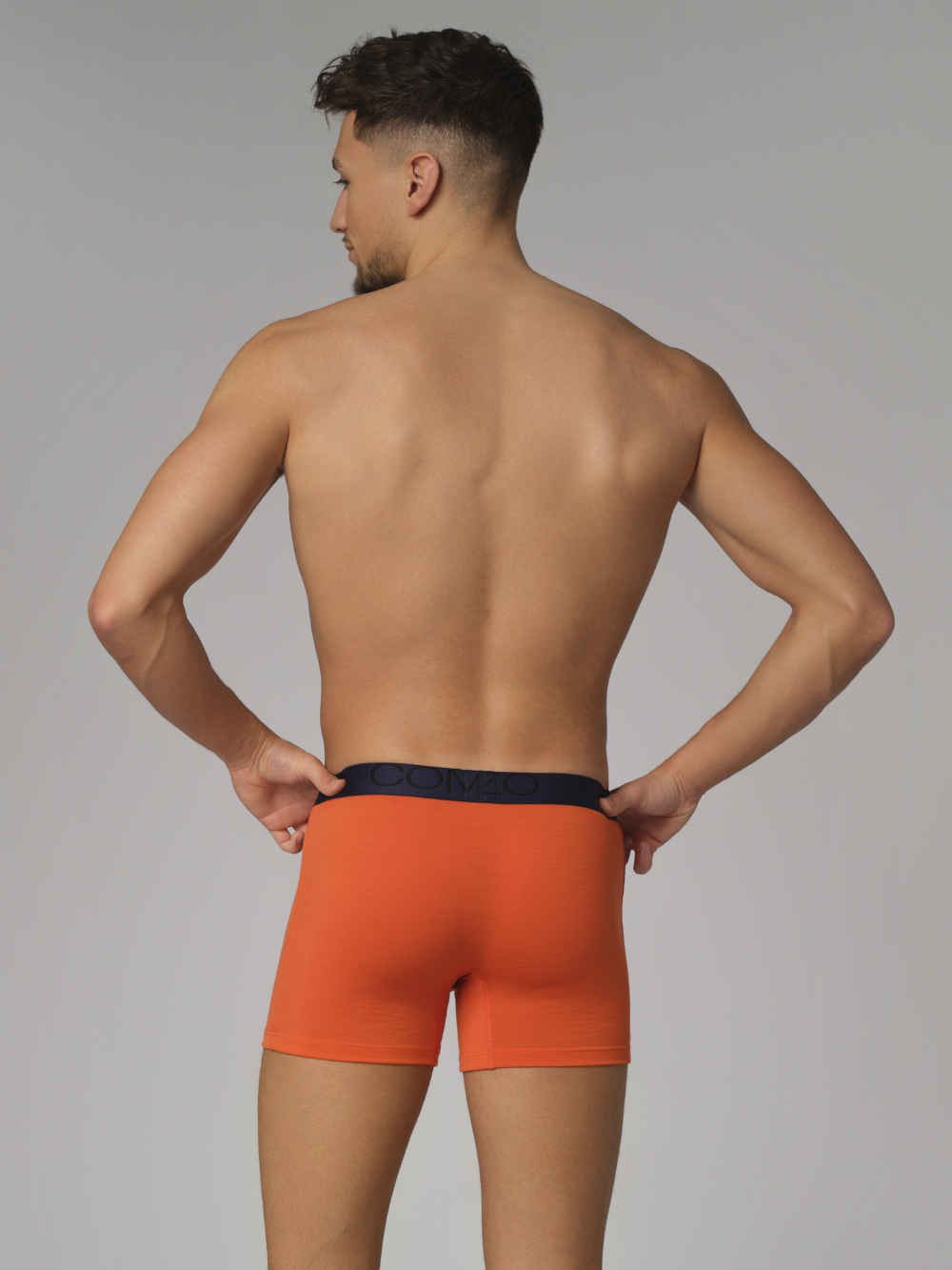 Rückansicht: Mann trägt Trunks von Comazo aus Merinowolle Farbe Orange/Granat
