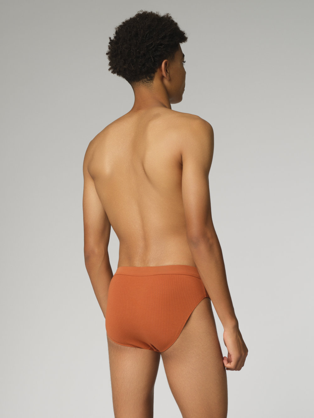 Rückansicht: Mann trägt Fairtrade Slip von Comazo in der Farbe Zimt mit Nadelzug
