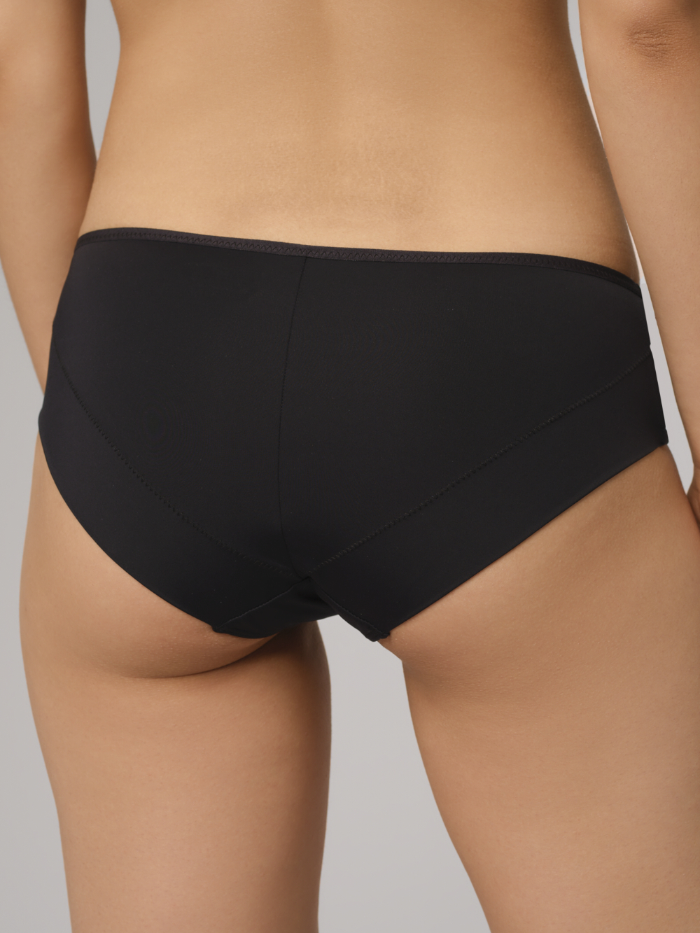 Close-up Rear View: Woman wearing a black Comazo panty with beautiful lace details