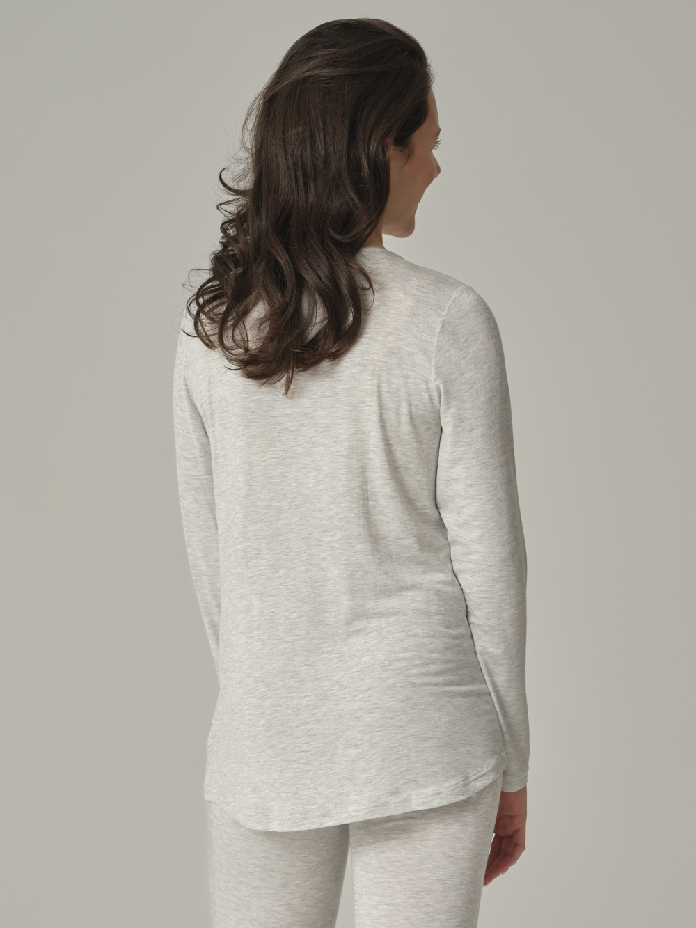 Rückansicht: Frau trägt Langarm-Schlafshirt aus Micromodal von Comazo in der Farbe Grau mit zarten Spitzen-Details