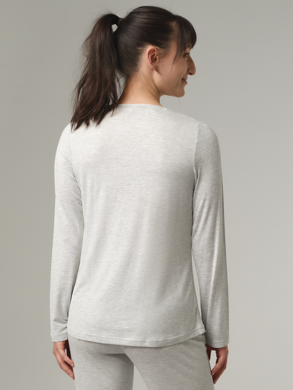 Rückansicht: Frau trägt Langarm-Schlafshirt aus Micromodal von Comazo in der Farbe Grau mit zarten Spitzen-Details