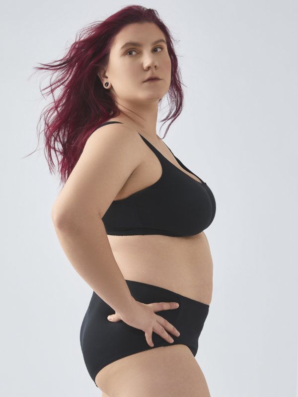 Seitenansicht: Frau trägt Komfort-BH mit Bügeln von Comazo in der Farbe Schwarz