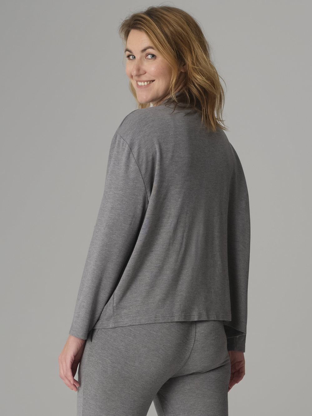 Rückansicht: Frau trägt Jacke von Comazo in der Farbe Grau-Melange mit Taschen auf der Vorderseite, Reißverschluss und Kragen mit Bändel